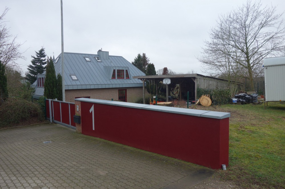 Haus und Garten hinter einer roten Grundstücksmauer